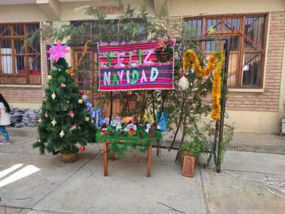 Ein geschmückter Weihnachtsbaum und ein buntes Tuch mit der Aufschrift Feliz Navidad